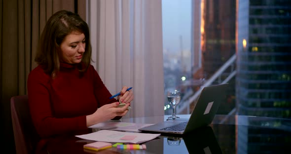 A Woman Sits at a Desk in the Office of a Business Center, in Front of Her Is a Laptop, on Which She