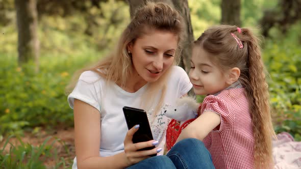 Little Small Child With Mother Make Video Call In Internet Social Network.  Girl Sitting With Mother