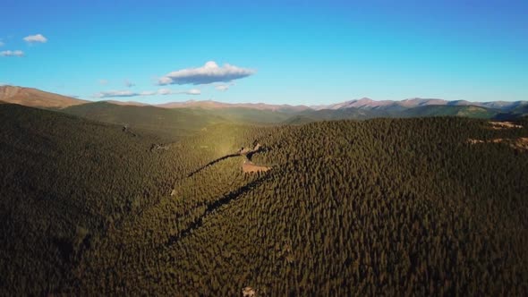 Drone shot of the mountain range densely covered with green pine forest in Colorado, USA