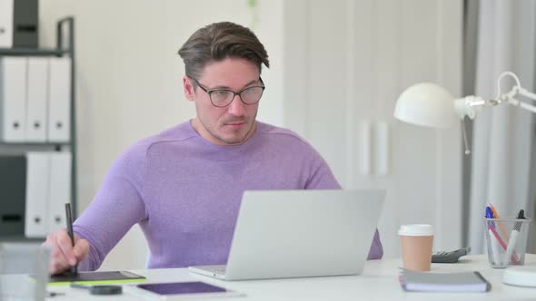 Middle Aged Man Using Graphic Tablet and Laptop for Designing 