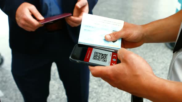 Airport male staff using mobile phone to scan the passport