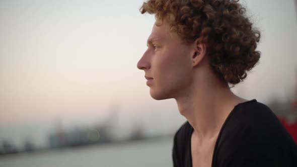 White Male with Red Curly Hair Looking at the Sea Black Shirt