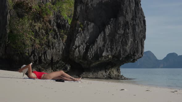 Young Woman Lying On Beach To Sunbathe In Sunhat