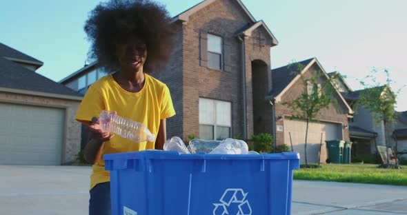 African American adolescence placing plastic bottles in recycle bin