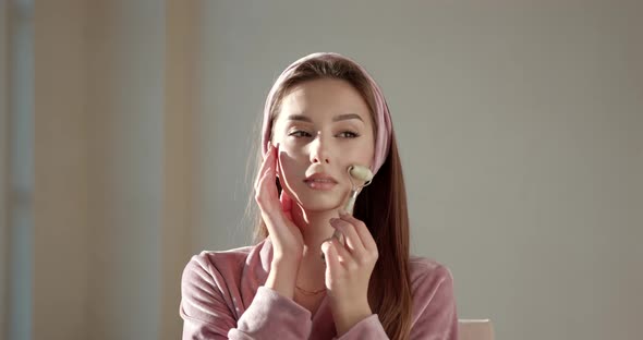 Woman Using Jade Facial Roller for Face Massage at Home