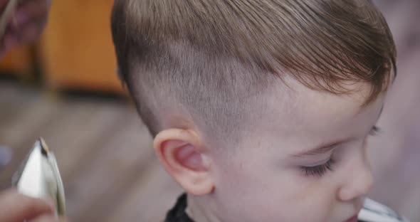 Children's Haircut in the Salon at the Time of the Coronavirus Epidemic. Little Boy Gets a Haircut