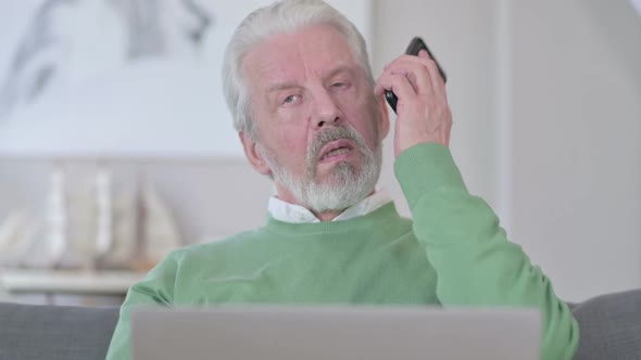 Close Up of Old Man with Laptop Talking on Smartphone