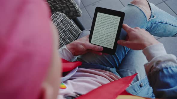 Caucasian Nonbinary Person Sitting on Balcony Holding His Small Handheld Electronic Device for