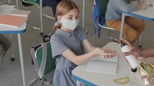 School Girl in Face Mask Using Sanitizer in Classroom