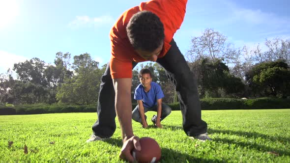 A father teaching his sons how to play American football.