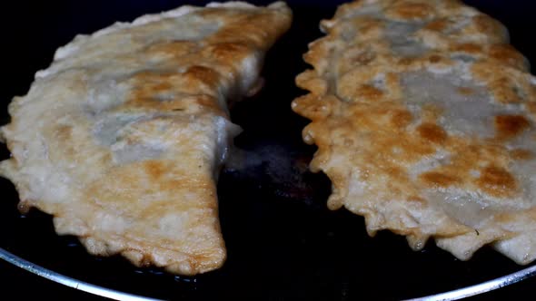 Pasties filling meat or cheburek fried in cooking oil in hot frying pan.