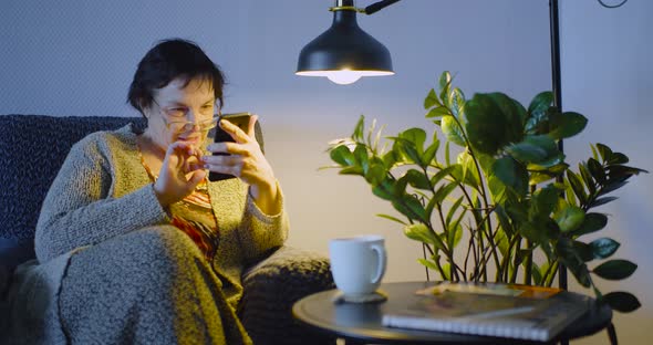 An Elderly Woman with Smartphone  She Searching Web Ang Watching Newsfeed