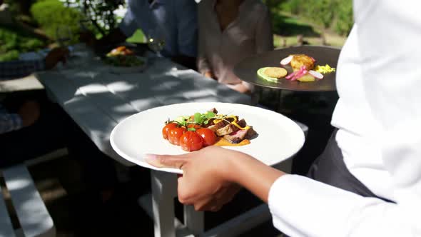 Waitress serving breakfast to group of friends