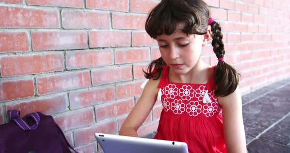 Schoolgirl using digital tablet in corridor at school