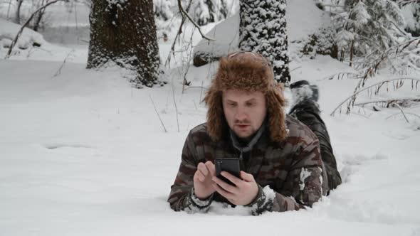 Forester Guy Lies in the Forest in the Snow and Writes a Message