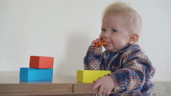 Joyful Baby Nibbles Orange Part at Low Wooden Table Closeup