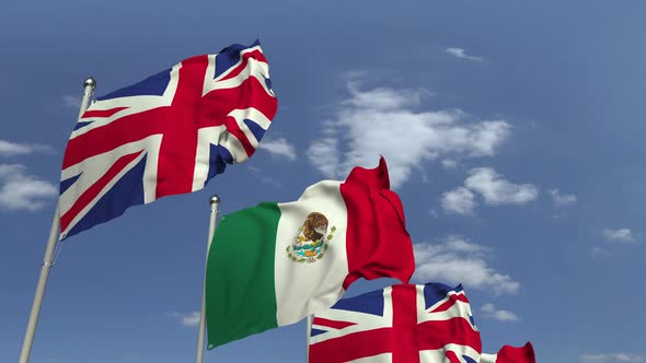 Waving Flags of Mexico and the United Kingdom on Sky Background