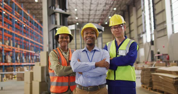 Portrait of diverse workers wearing safety suits and smiling in warehouse