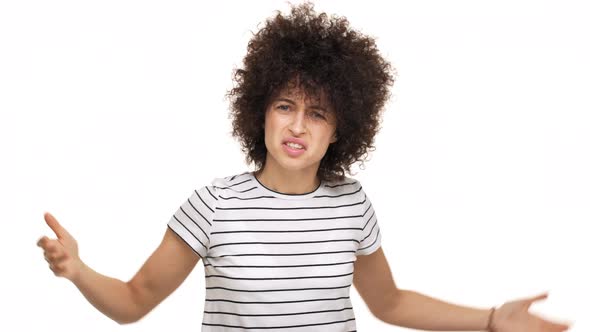 Indoor Portrait of Aggressive Young Curly Woman in Casual Tshirt Gesturing with Annoyance Sorting