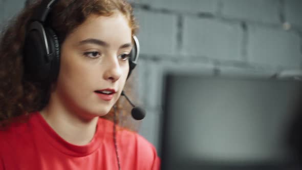 Young Girl Gamer in Headphones Plays a Video Game and Communicating with a Team of Players Cyber