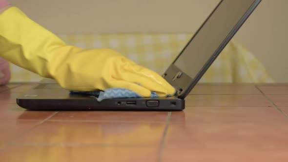 Hands in rubber gloves cleaning laptop with cloth medium shot