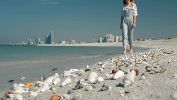An Unrecognized Young Girl in Sunglasses Walks Along the Beach Against a Backdrop of Beautiful