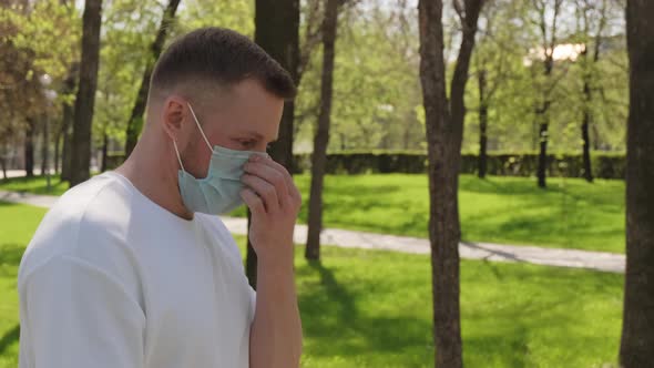 Man in Face Mask Walking in Park on Summer Day