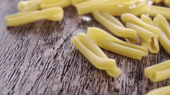 Raw yellow casarecce pasta on rustic wooden board. Macro