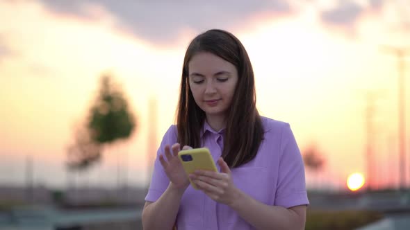 Female Person Walking in the Sunny Streets Typing on Phone