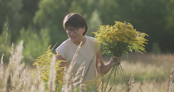 Woman is Picking Solidago Commonly Called Goldenrods on Autumn Field
