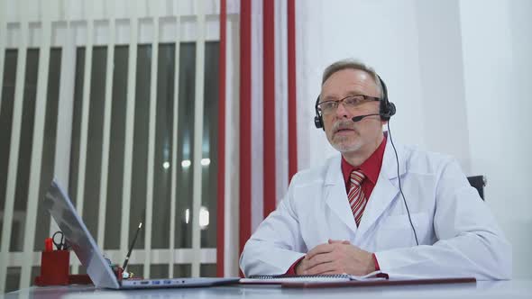 Video conferencing with patient. Doctor in front of laptop talking online with patient