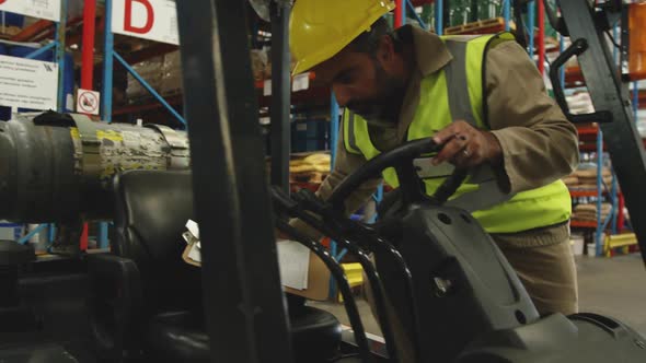 Male worker driving forklift in a warehouse