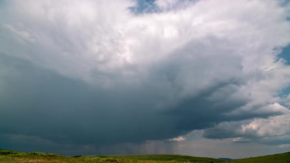 Dark clouds move over mountain meadow during rainstorm