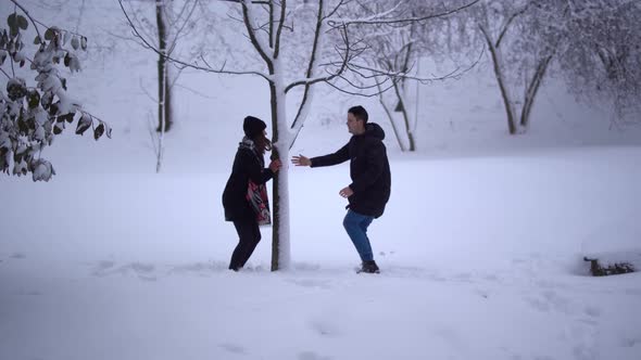 Cute Young Man and Girl Spend Their Leisure Time in a Snow-covered Park