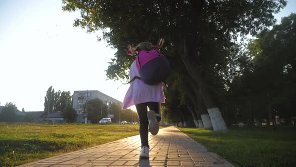 Little Girl with a Backpack Run To School. School and Kindergarten Education Concept. Back View