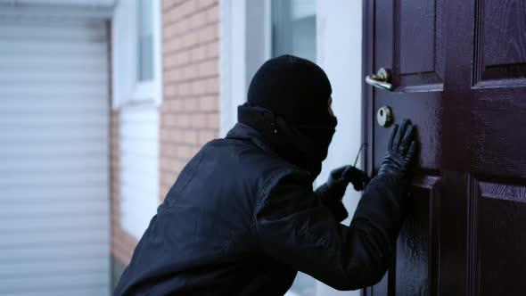 Man in Balaclava Breaking in House Picking the Lock Outdoors