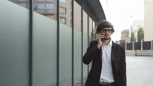 A businessman is talking on the phone on his way to work in a big city.