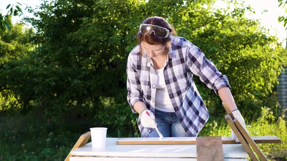 Adult Crafts Woman Painting Wooden Planks with White Paint in Summer Orchard