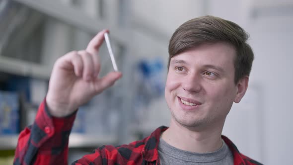 Closeup of Young Brunette Man with Brown Eyes Looking at Drill Bit