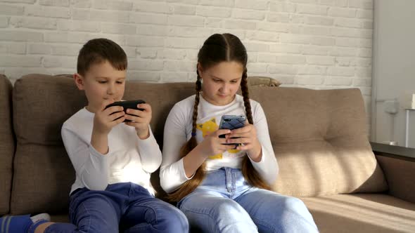 Children play with gadgets. Play online games at home on the couch. Parents control