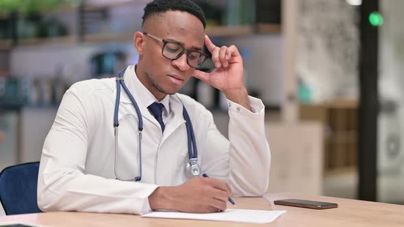 Focused African Male Doctor Doing Paperwork in Office 