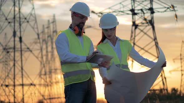 People Working at a Power Line, Look at a Tablet. .