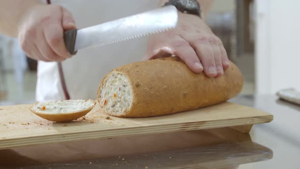 Baker is Cutting Baked Dutch Bread with Raisins and Dried Apricots with Knife