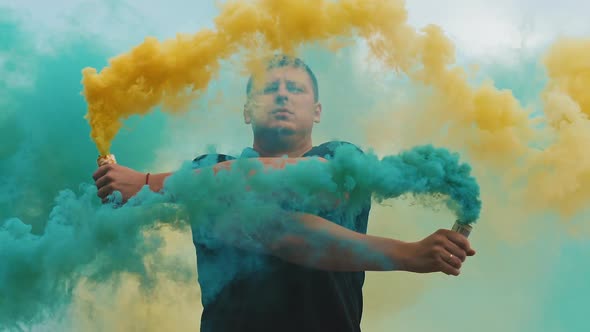 Man with Yellow and Blue Colored Smoke Bomb