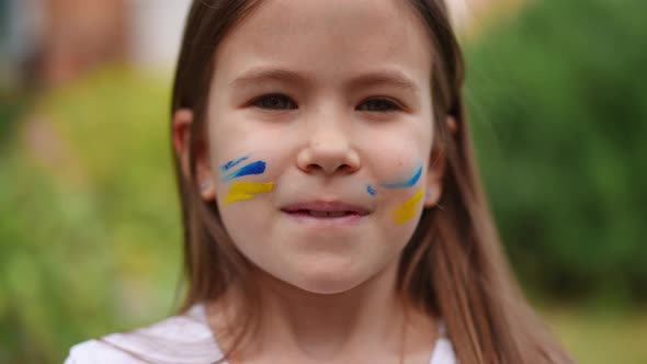 Headshot of Patriotic Charming Ukrainian Girl with Face Painting Looking at Camera and Looking Away