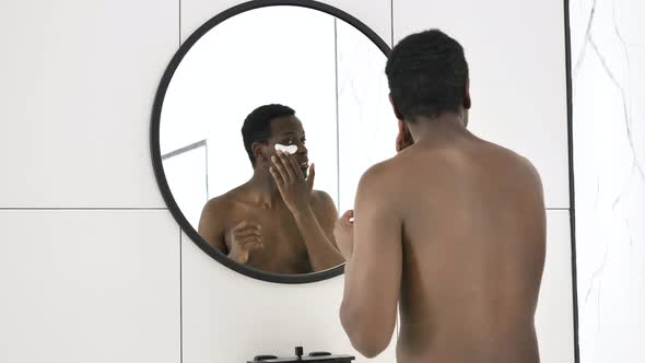 Cheerful AfricanAmerican Guy Dances at Mirror in Bathroom