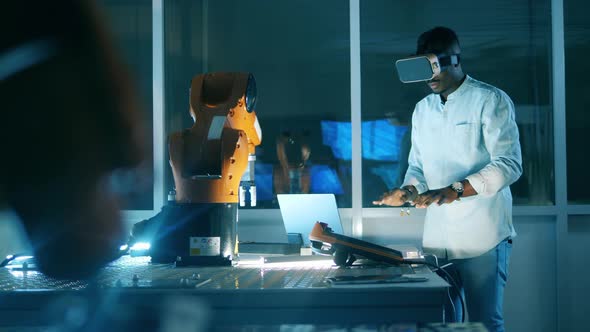 African Scientist in VRglasses Is Operating a Robotic Arm