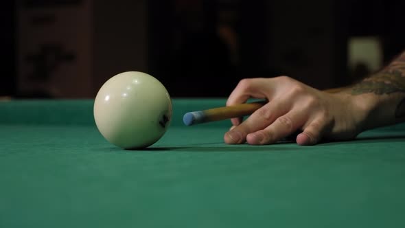 Closeup of a Man Hitting a Billiard Ball with a Cue That Stands on a Green Table