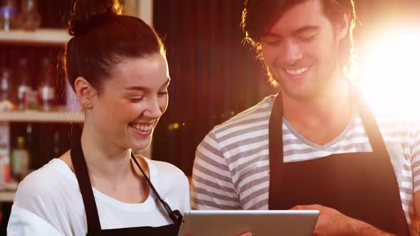 Waiter and waitress discussing over digital tablet