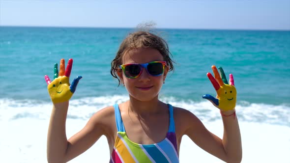 A Child at the Sea with Paints on Her Hands a Smile
